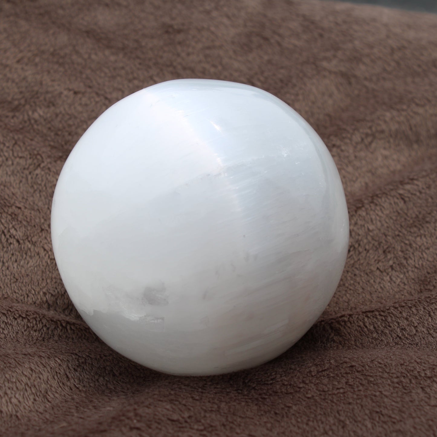 Satin spar selenite sphere with a smooth, polished surface ideal for meditation or home decor