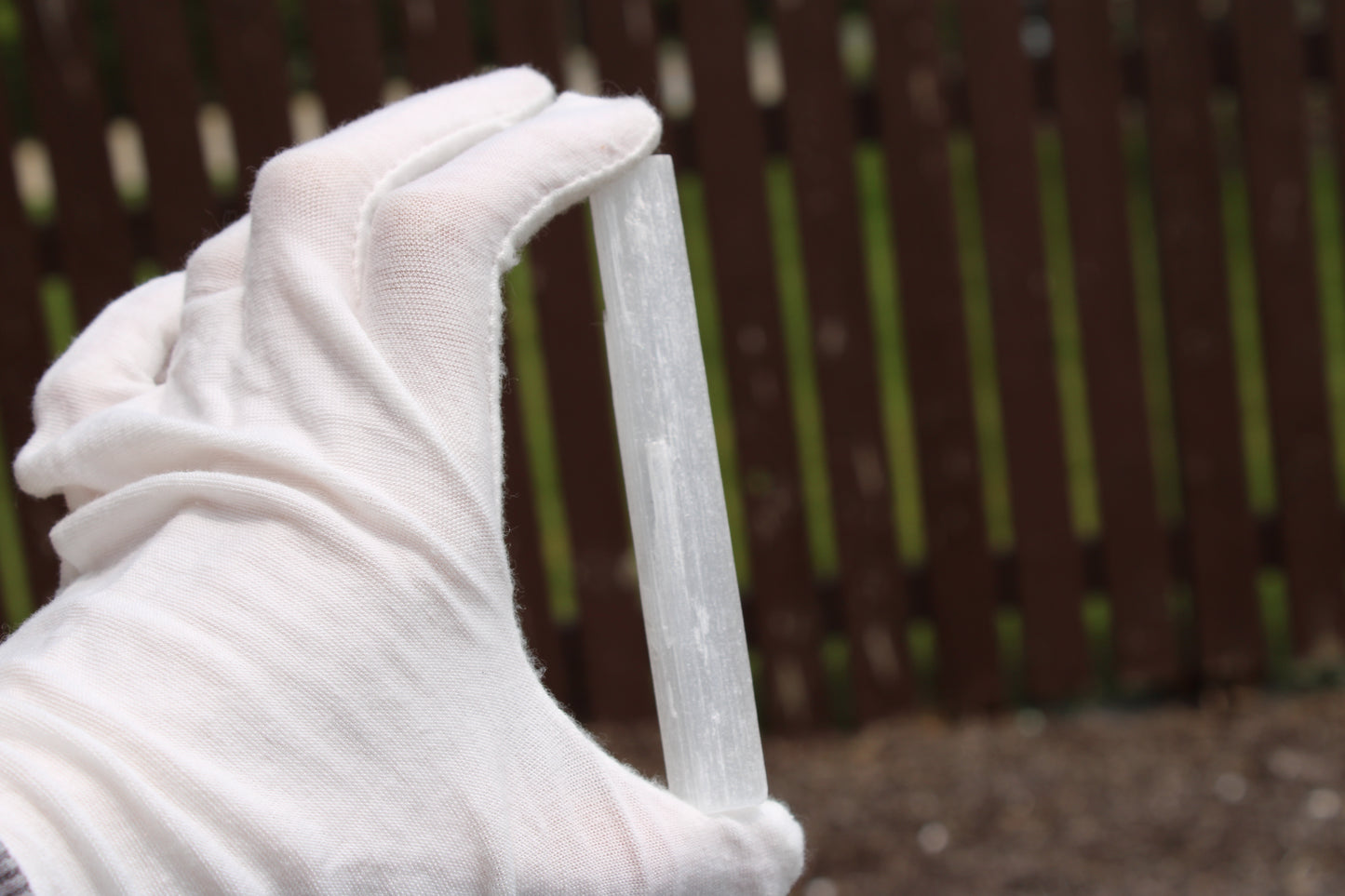 Person holding a Satin Spar Selenite stick showcasing its smooth and elegant surface in natural light