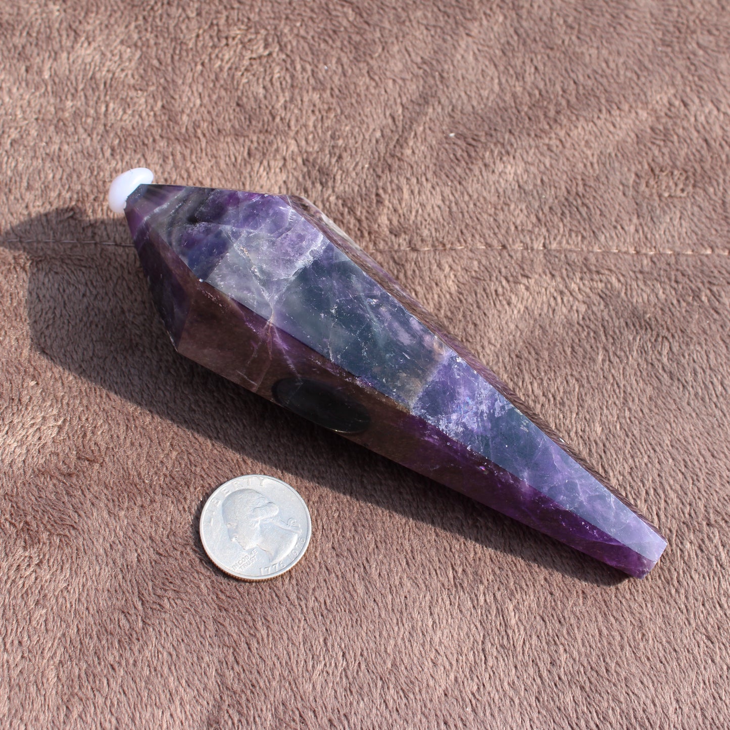 Thick Amethyst Wand crystal by Different Branches LLC next to a quarter for size reference
