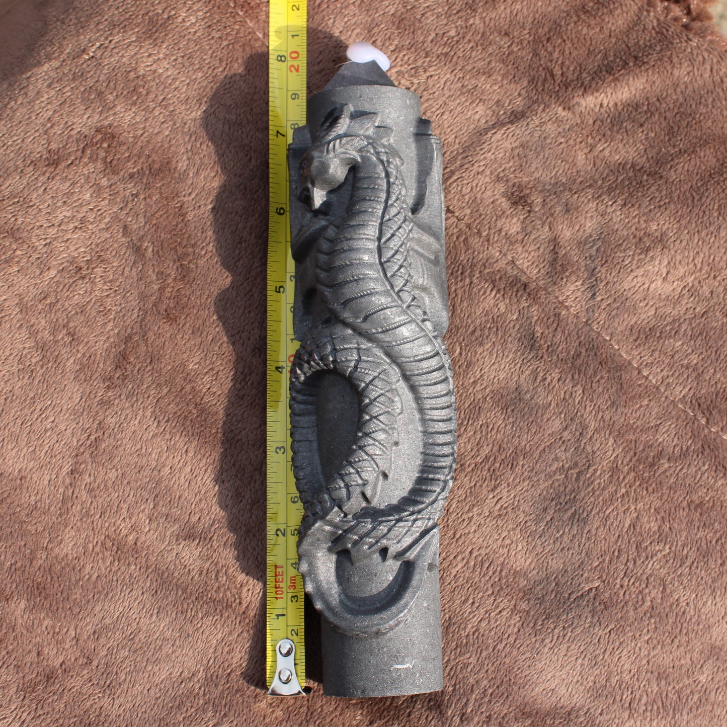Shungite Dragon Tower crystal with intricate dragon carving and measuring tape for size reference