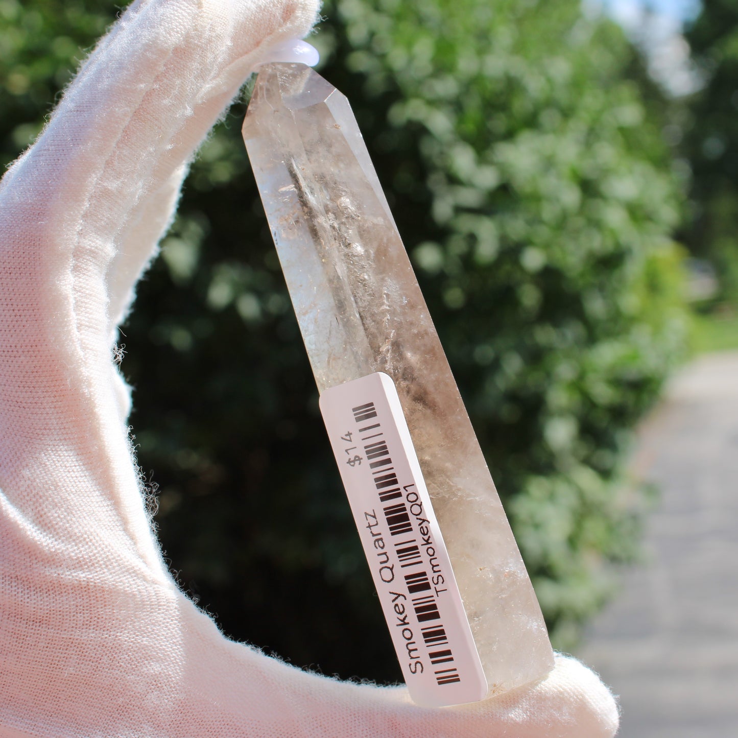 Smokey Quartz Tower crystal held by gloved hand with outdoor background from Different Branches LLC