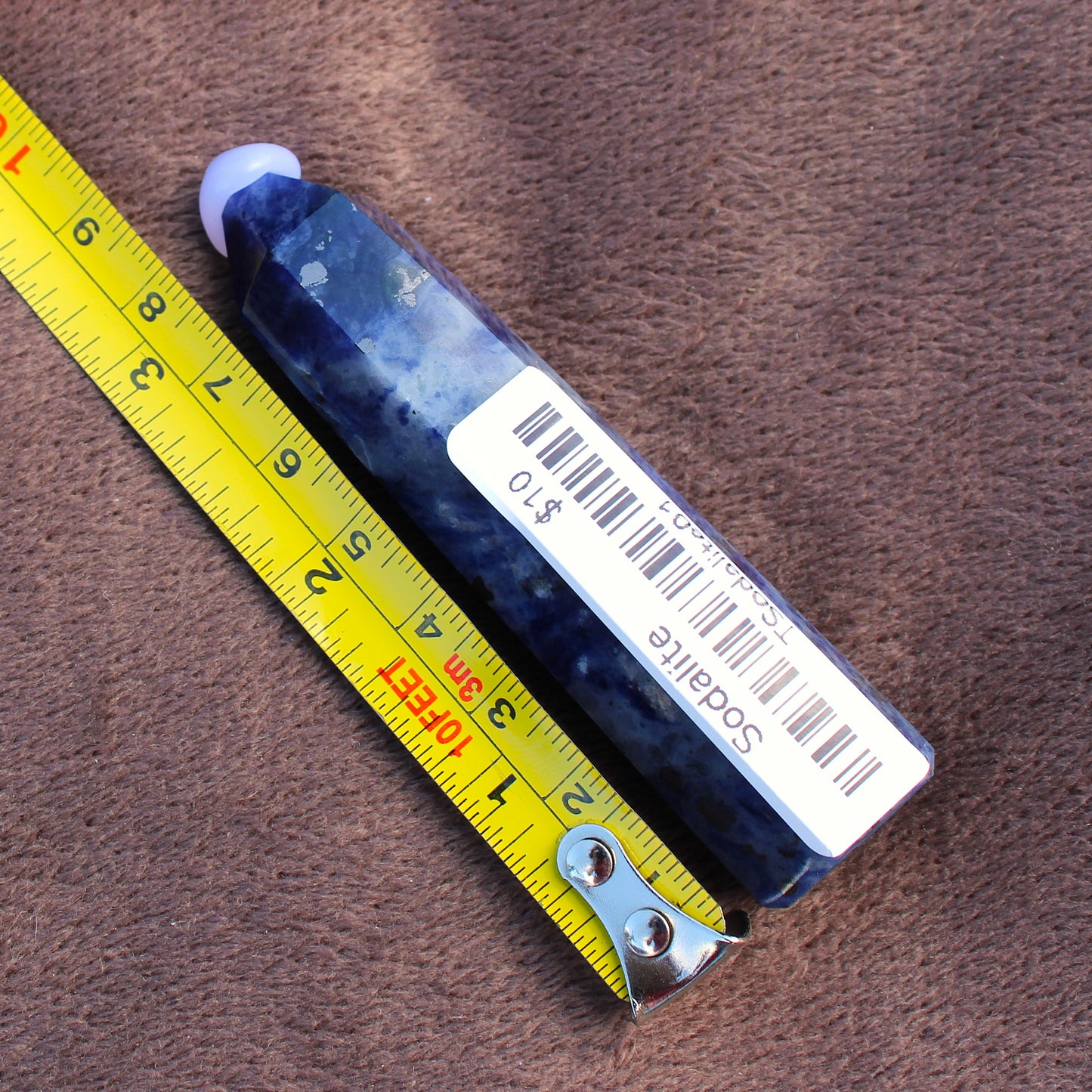 Sodalite Tower crystal from Different Branches LLC with price tag and measuring tape on brown fabric