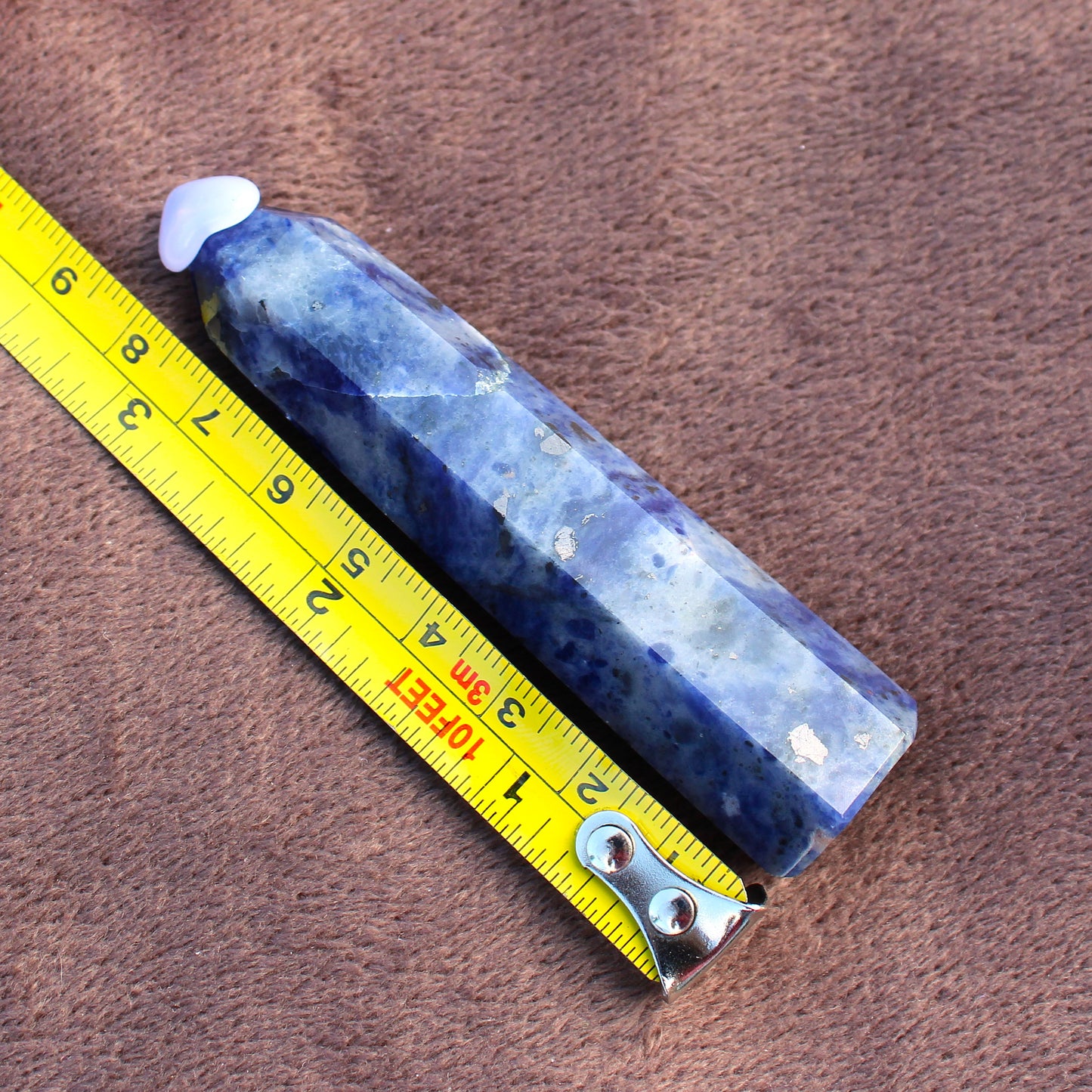 Sodalite Tower crystal with blue and white patterns placed next to a yellow measuring tape
