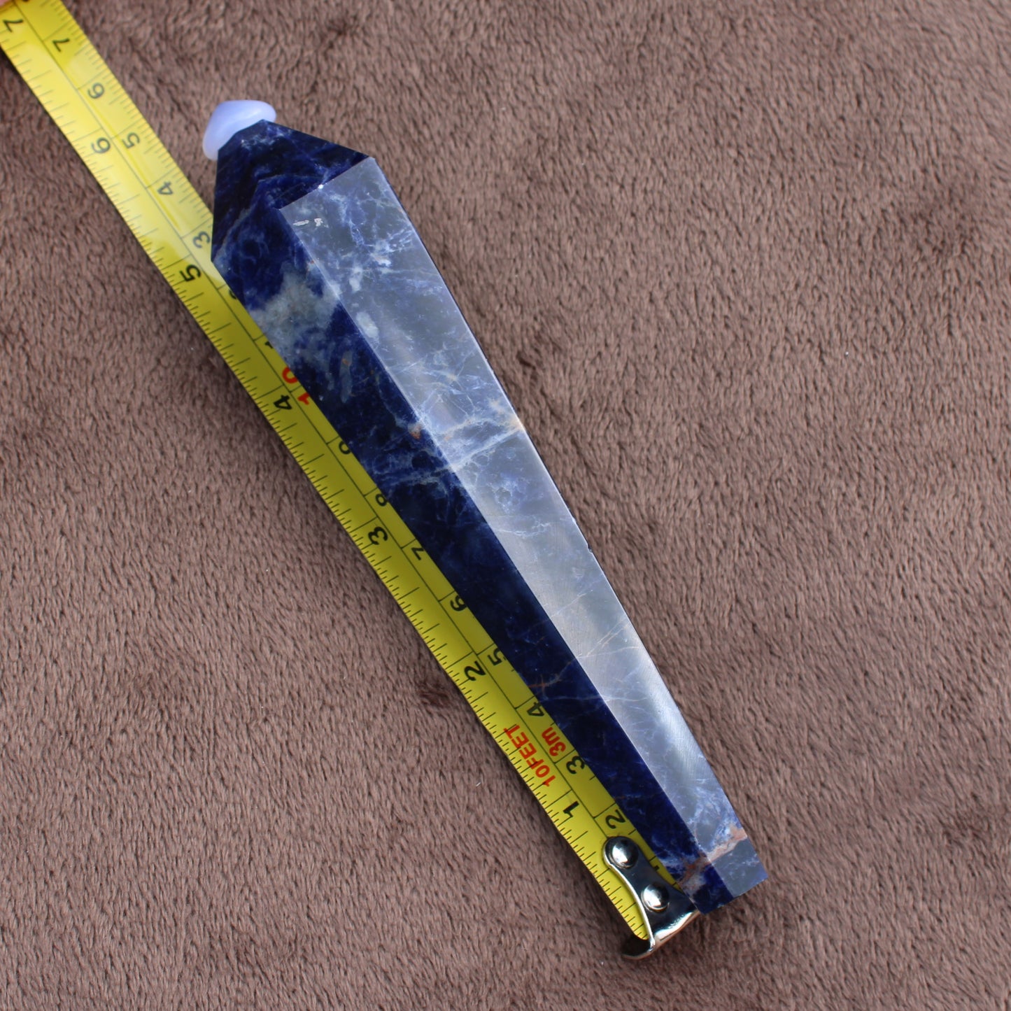 Sodalite Wand crystal from Different Branches LLC placed next to a measuring tape showing its length