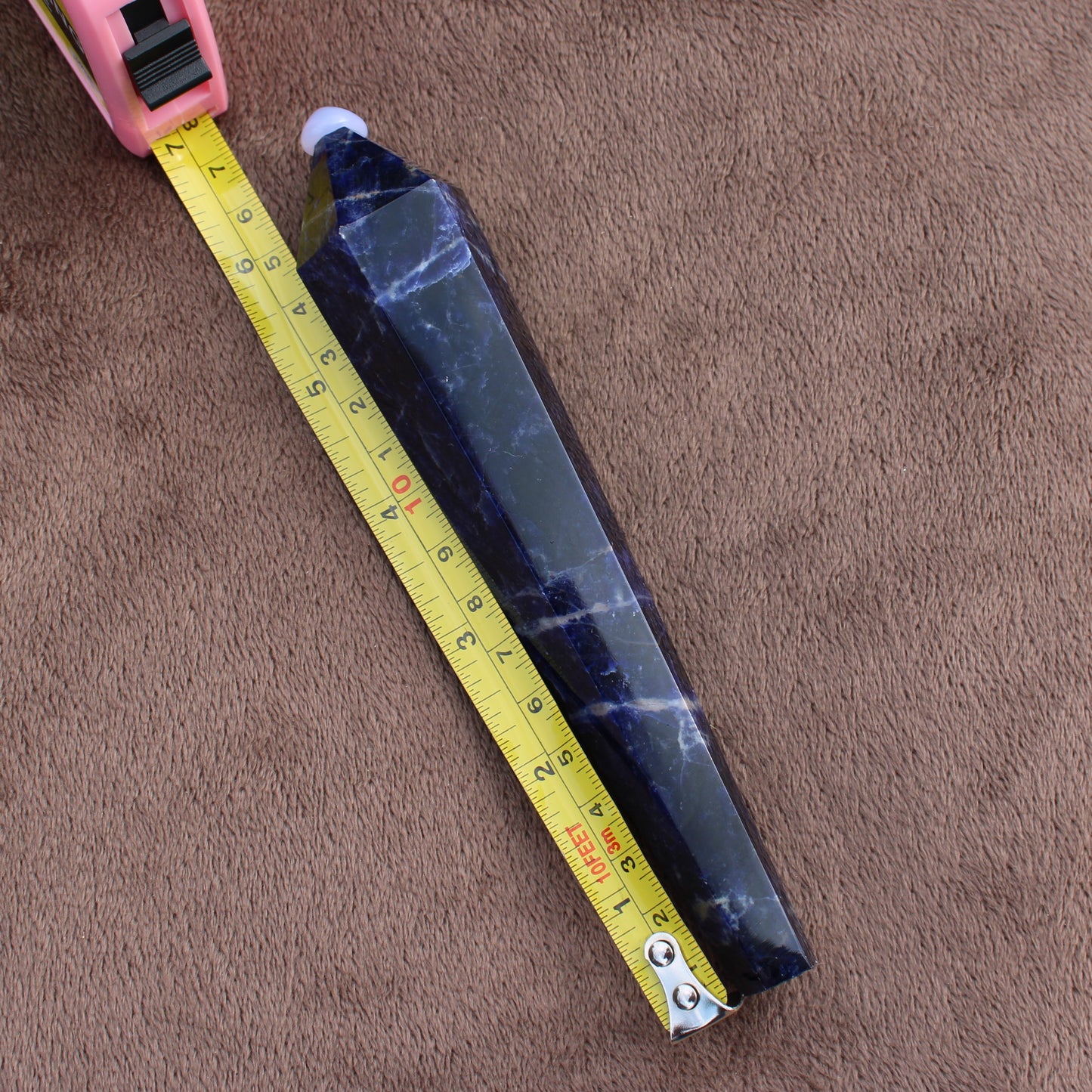 Sodalite Wand crystal from Different Branches LLC measured with a yellow tape on brown fabric background