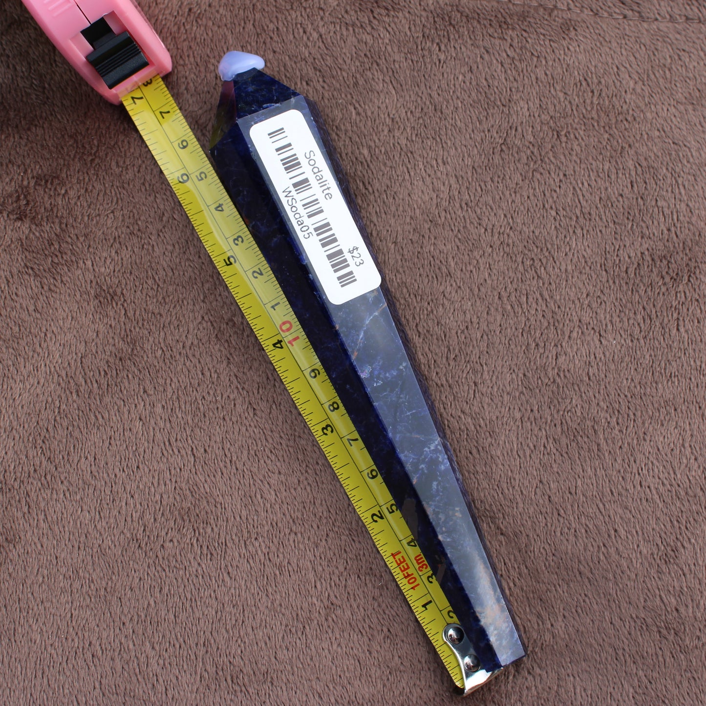 Sodalite Wand crystal from Different Branches LLC measured with a yellow tape on brown fabric