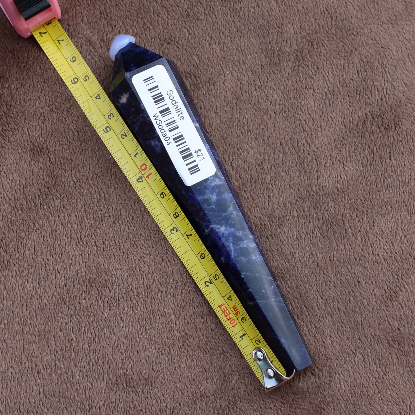 Sodalite Wand crystal from Different Branches LLC shown next to measuring tape on brown fabric background