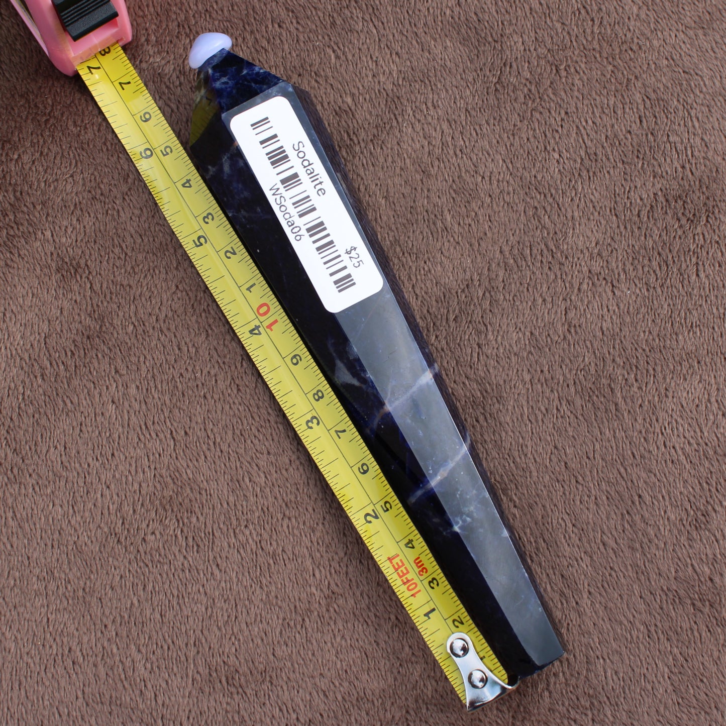 Sodalite Wand crystal from Different Branches LLC measured next to a tape measure on brown fabric