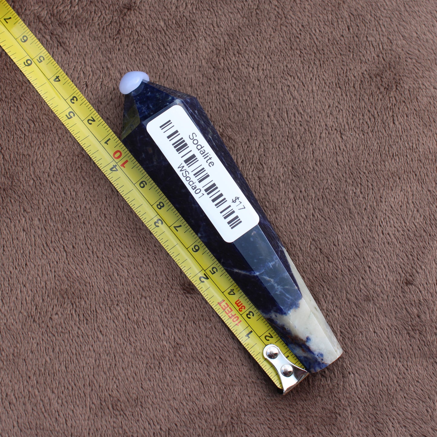 Sodalite Wand crystal from Different Branches LLC next to measuring tape on brown surface