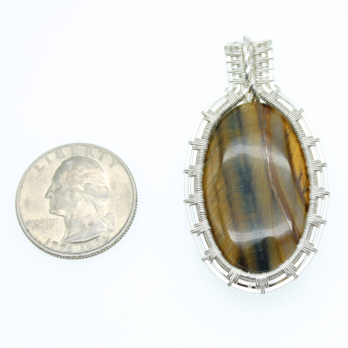 Sterling wire wrap pendant collection featuring a polished tiger's eye stone next to a quarter for scale