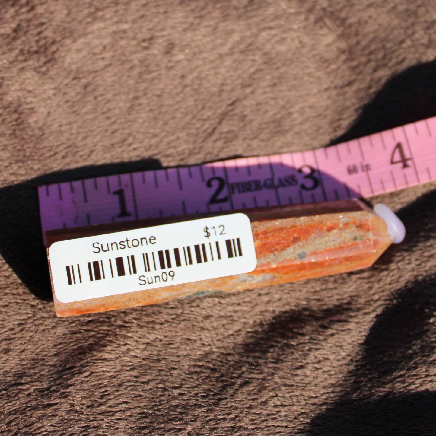 Sunstone tower crystal with natural orange hues and measurement in inches for display purposes