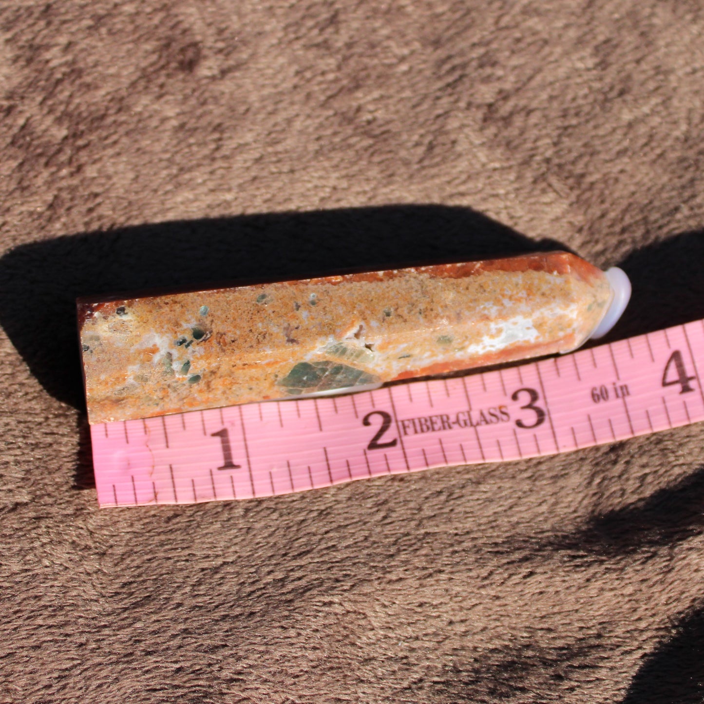 Natural Sunstone tower displayed on a measuring tape for size reference