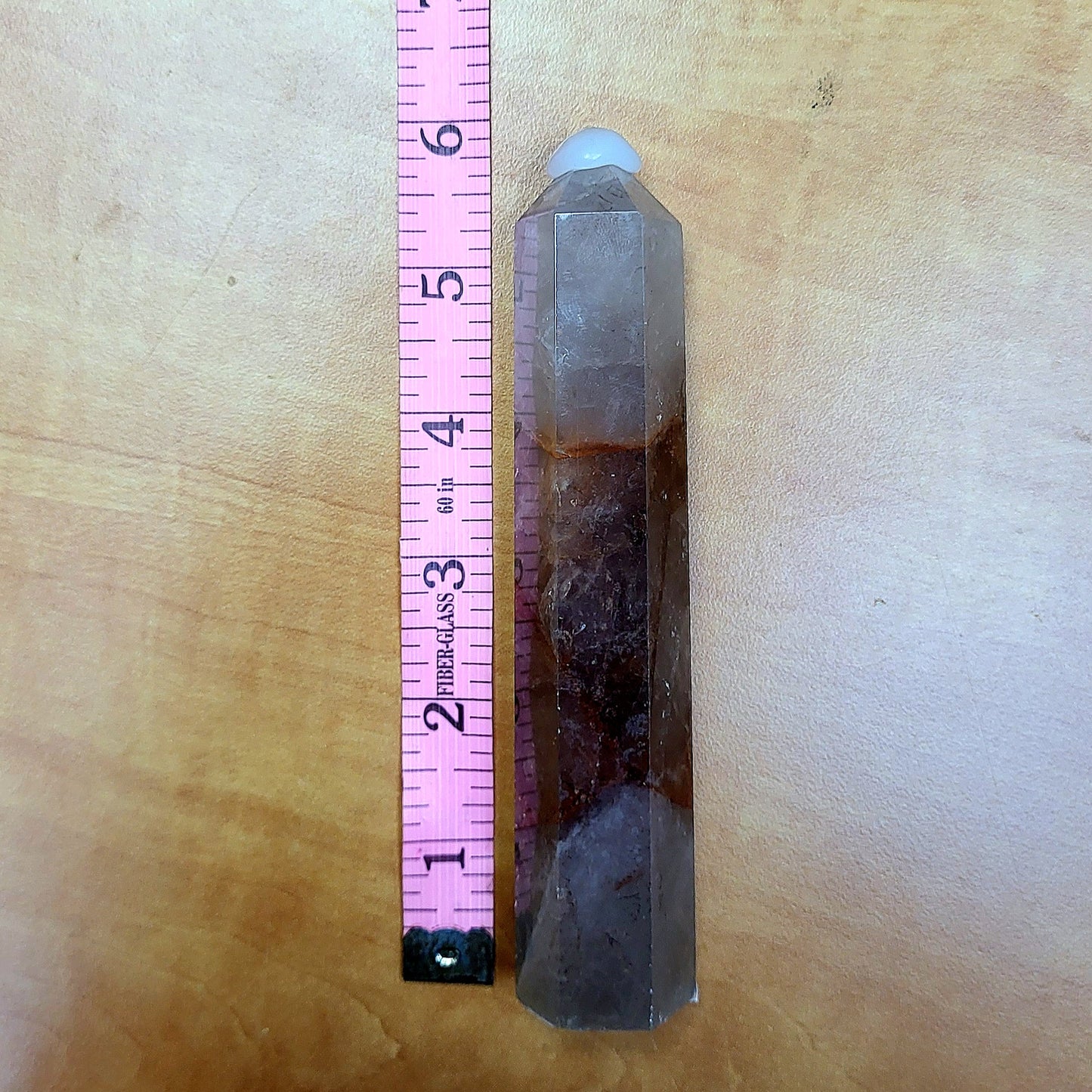 Tall Fire Quartz Tower with distinct color variations, placed next to a ruler for size reference