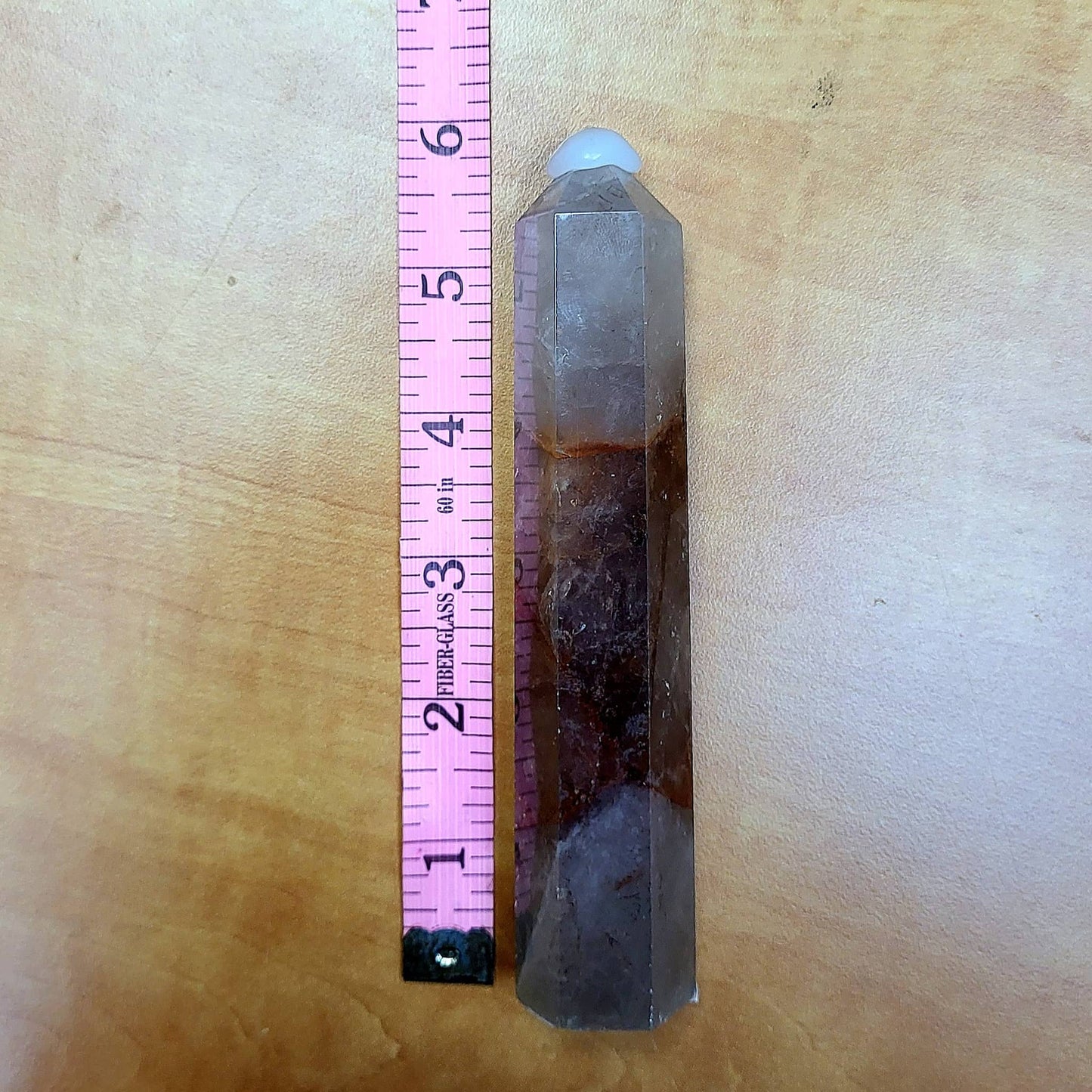Tall Fire Quartz Tower with distinct color variations, placed next to a ruler for size reference