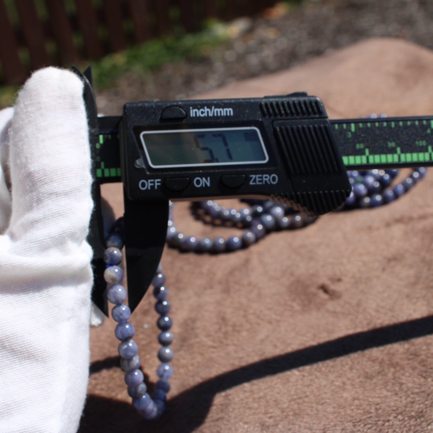 Measuring a Tanzanite Bracelet with a caliper showing 57mm for accurate sizing