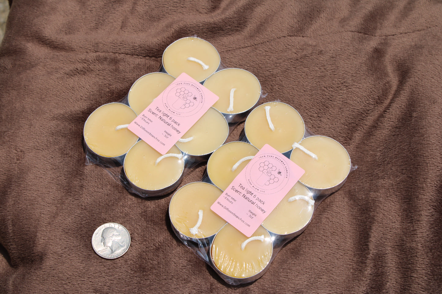 Pack of tea light candles pack displayed on a soft surface with a quarter for size comparison
