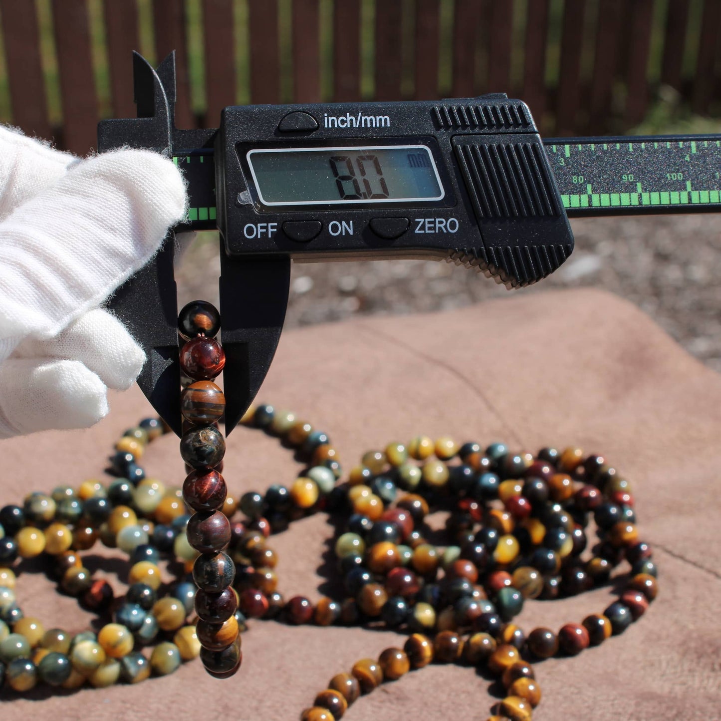 Caliper measuring a Tiger eye Bracelet among various crystal bracelets for accurate sizing