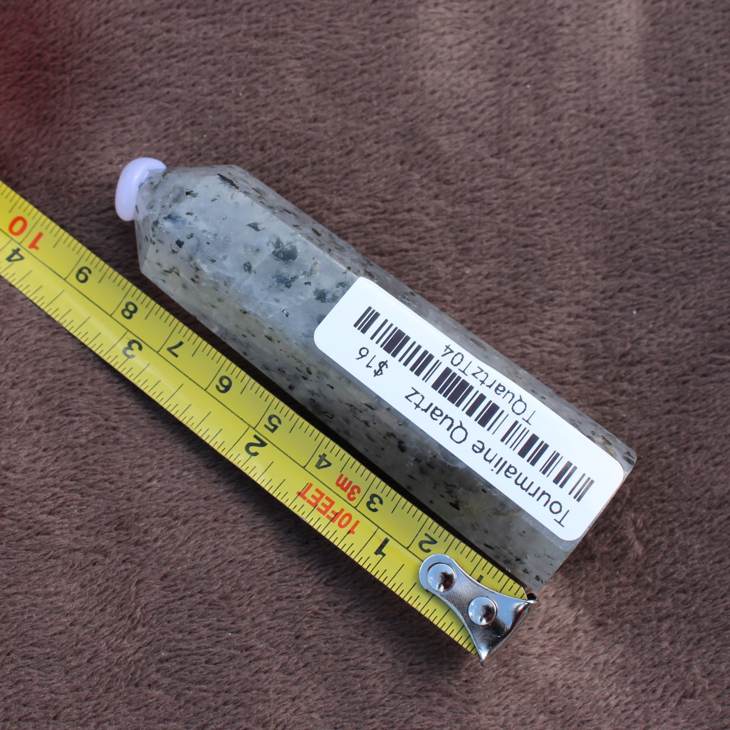 Tourmalited Quartz Tower crystal measuring approximately 4 inches placed on a brown fabric background