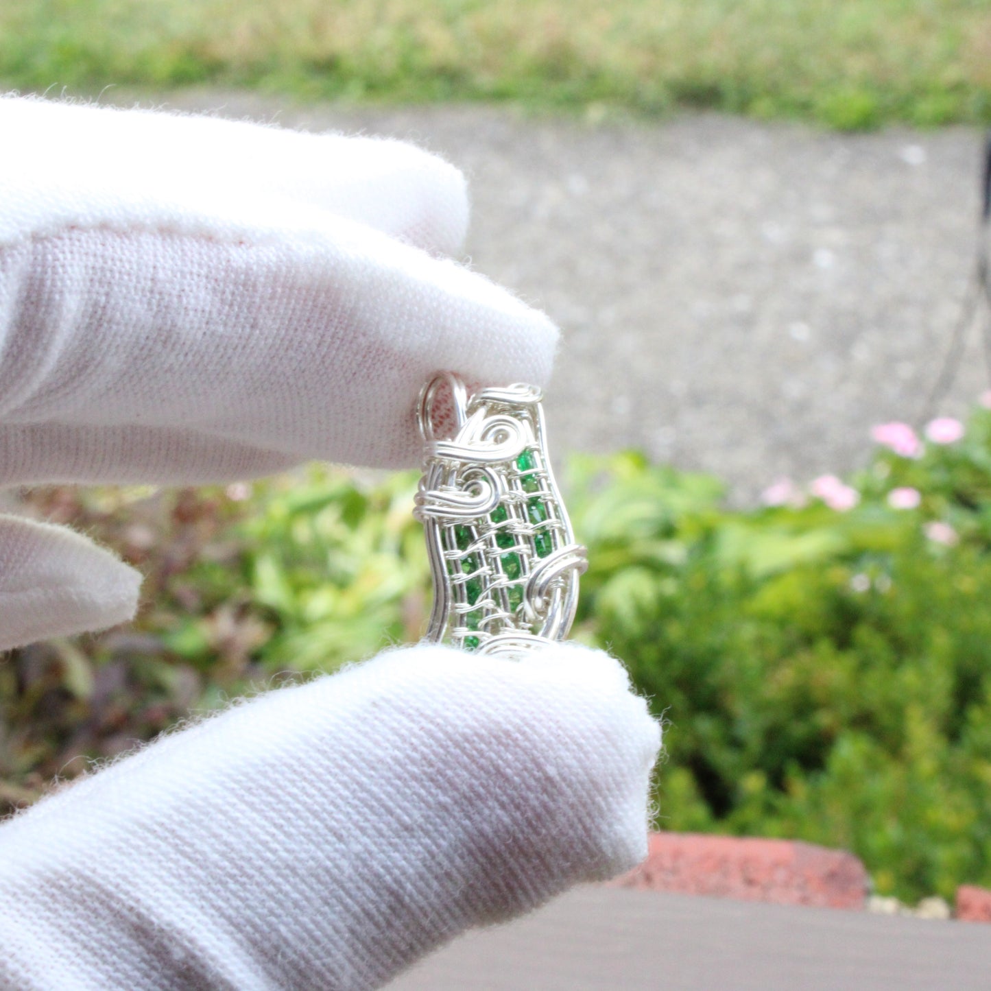 Tsavorite Sterling silver Pendant held in a gloved hand showcasing intricate design and vibrant green stones