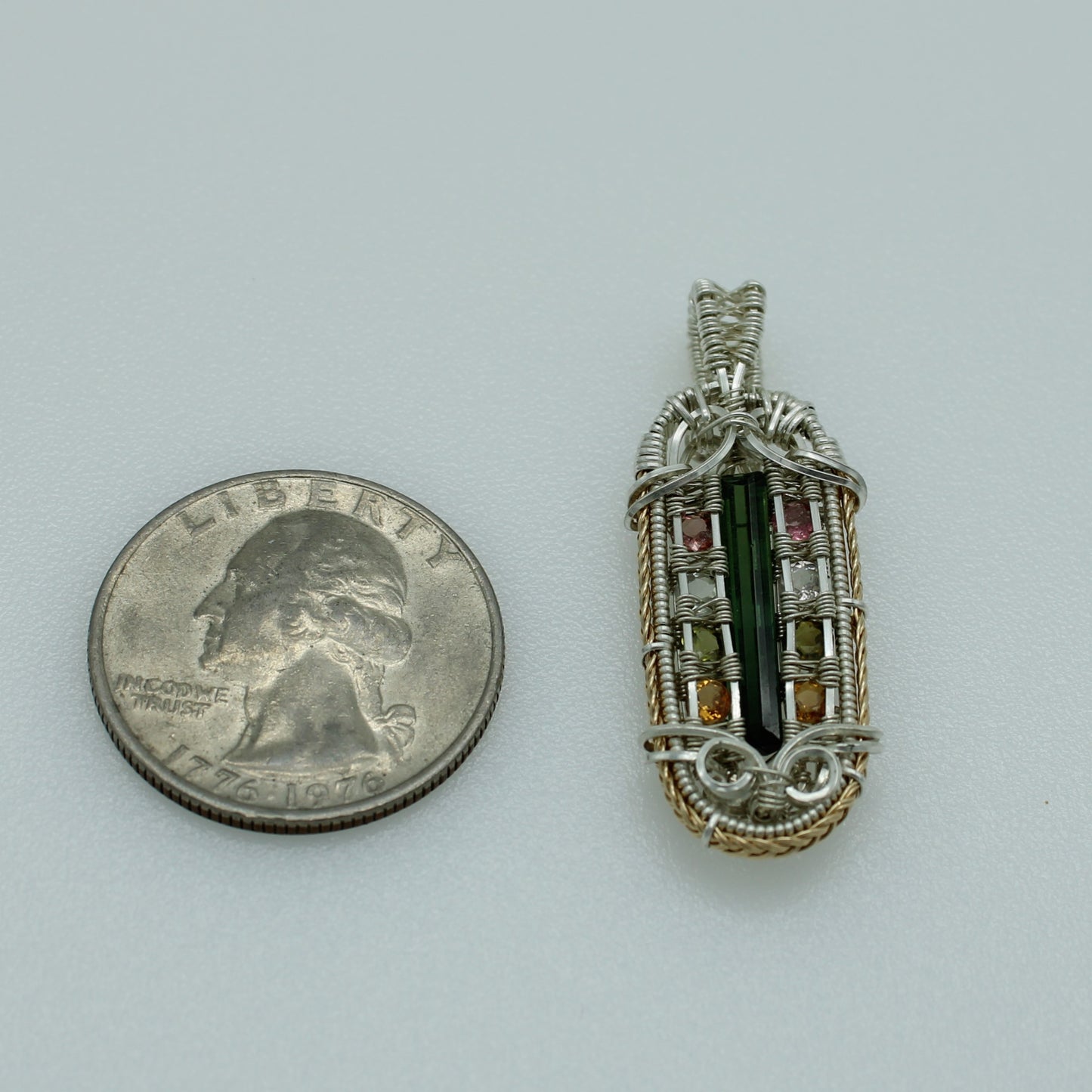 Unique crystal jewelry Richfield featuring a wire-wrapped pendant with colorful crystals next to a quarter for size reference