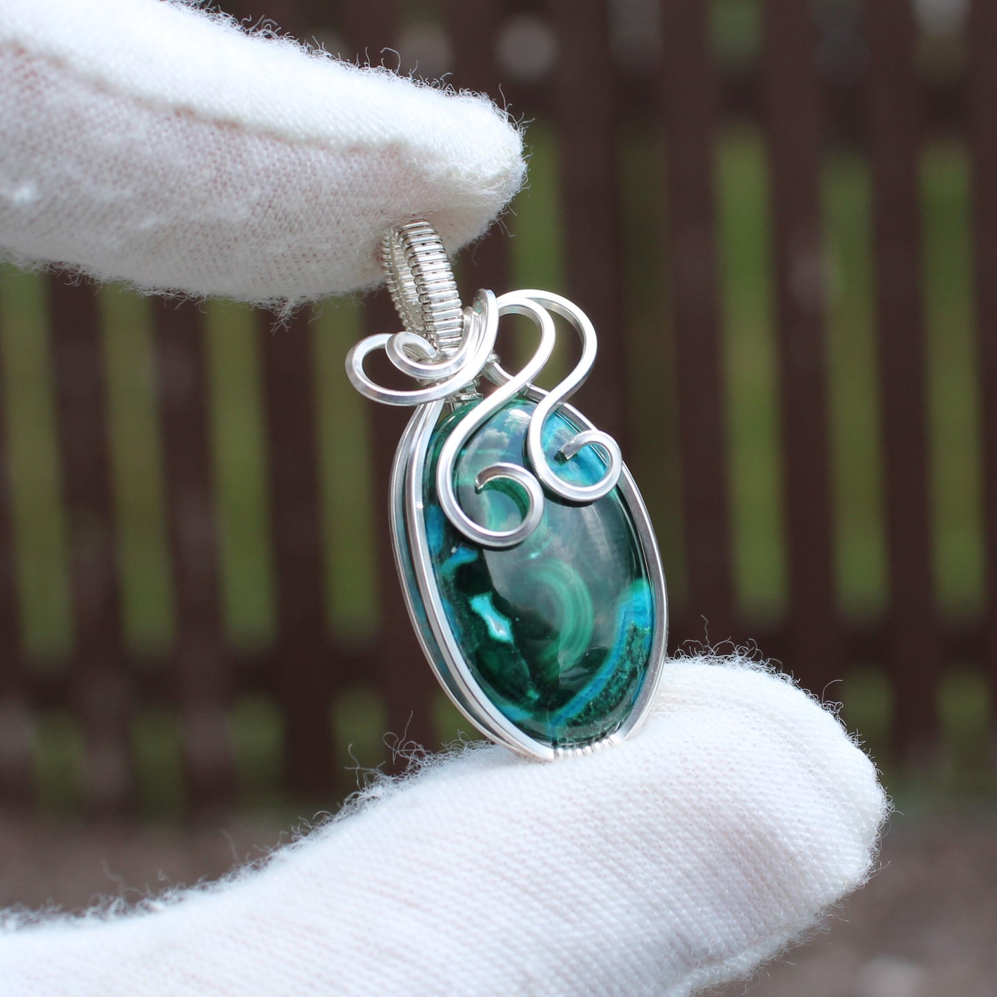 Sterling Silver Chrysocolla Malachite pendant with intricate wire wrapping held by hand