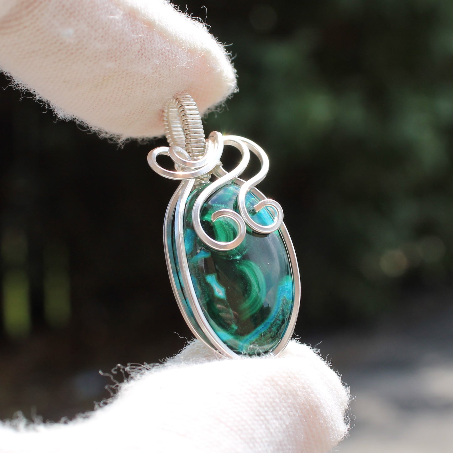 Sterling Silver Chrysocolla Malachite pendant with intricate wire wrapping held by gloved