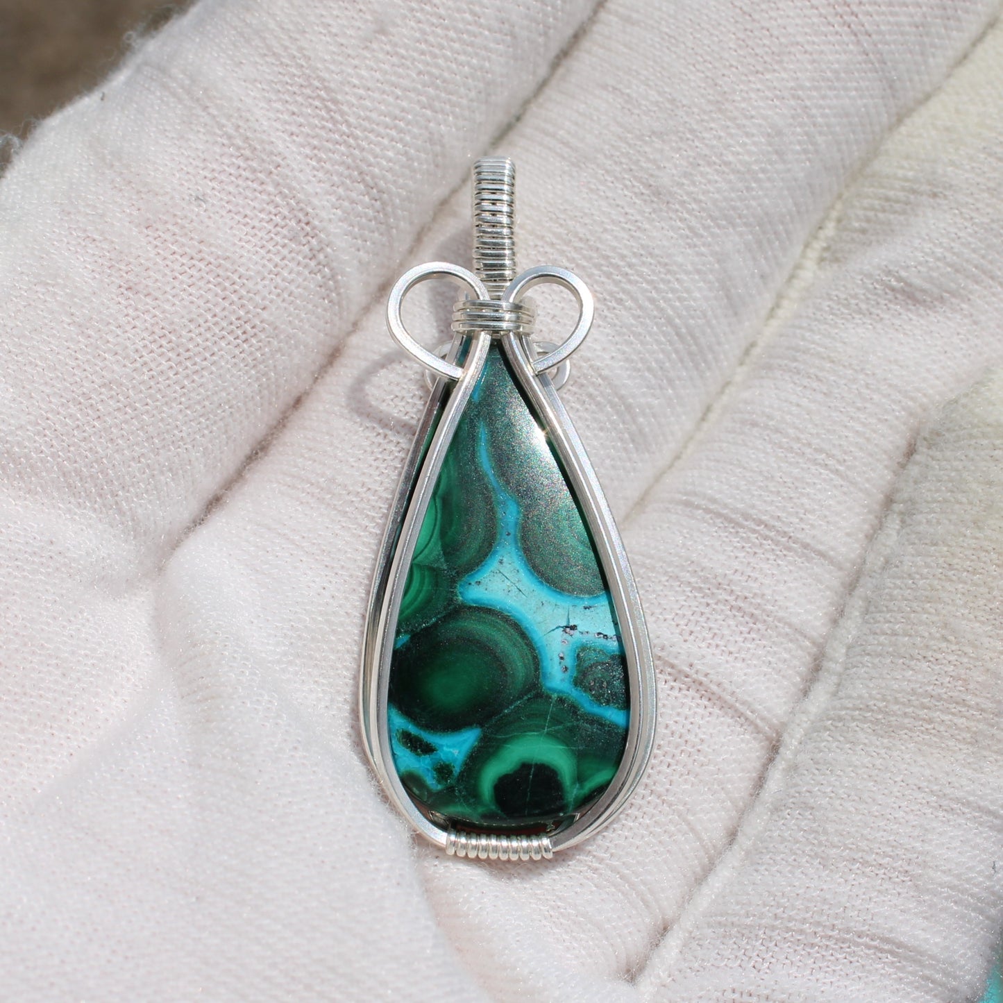 Sterling silver chrysocolla malachite teardrop pendant held in a white-gloved hand