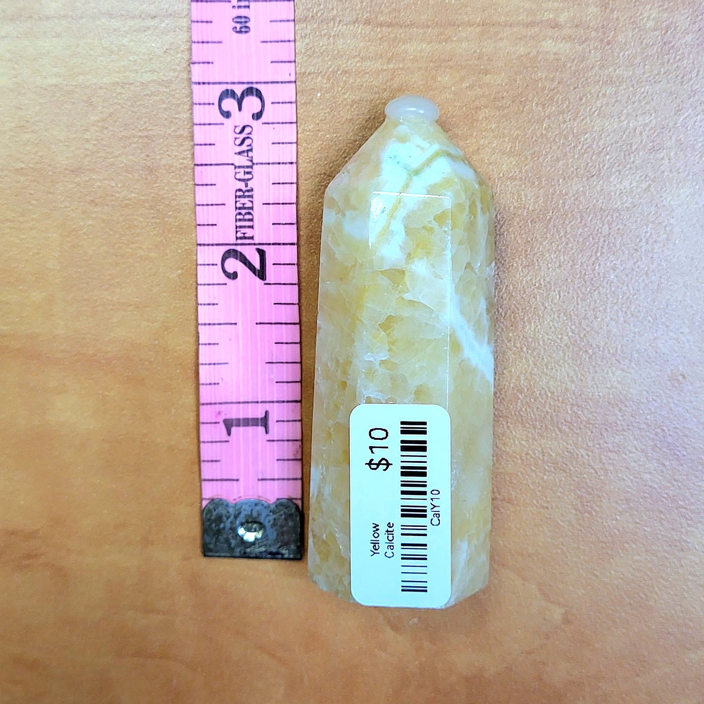 Yellow Calcite Towers with a smooth surface and tapered top, alongside a ruler for size comparison