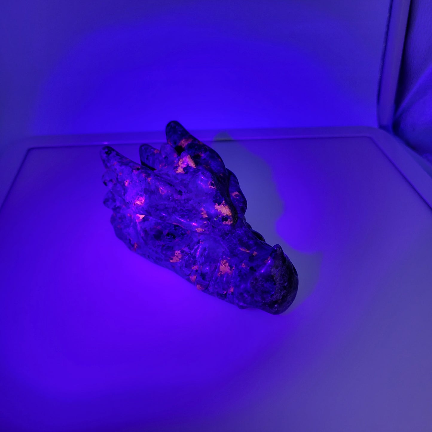 Yooperlight dragon head sculpture glowing under ultraviolet light, showcasing unique crystal features