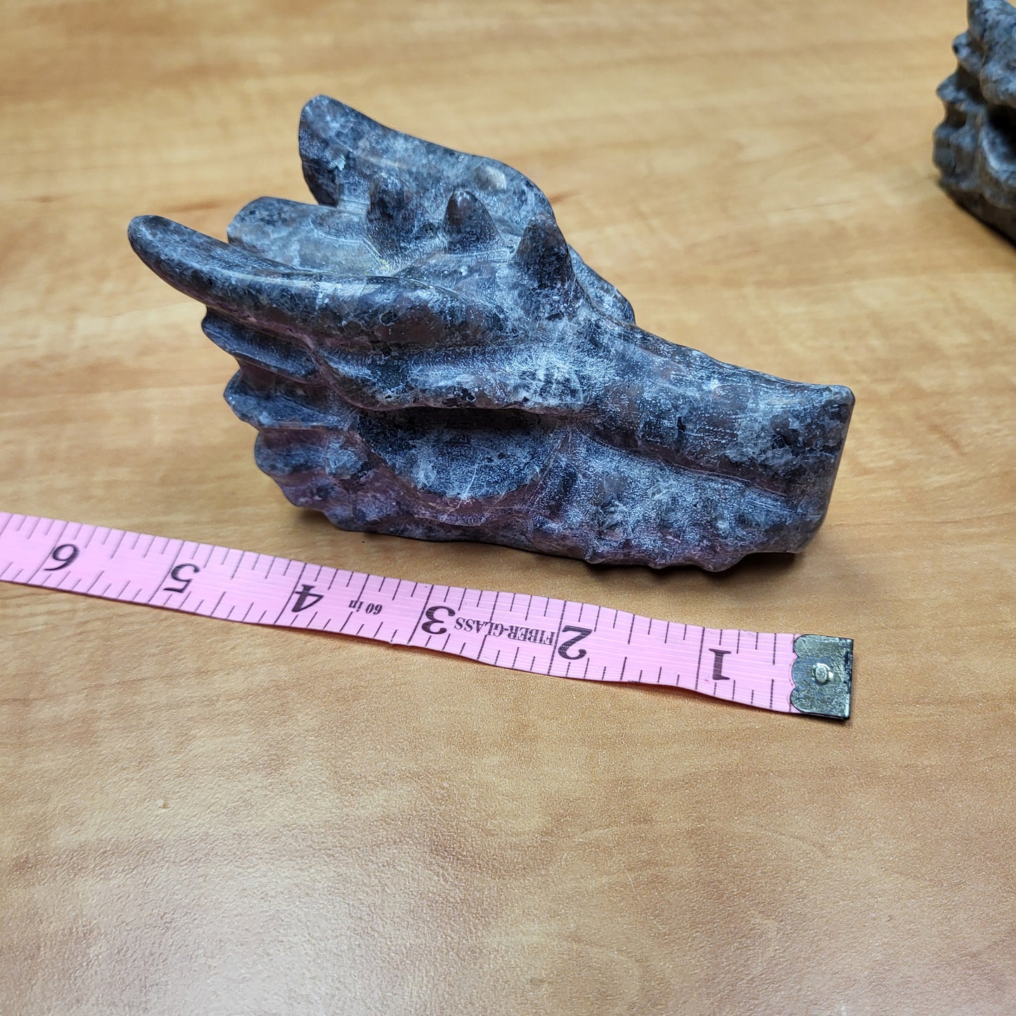 Yooperlight dragon head sculpture in dark stone with intricate details on a wooden surface