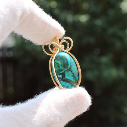 14k Gold Filled Chrysocolla Malachite pendant with gold wire wrapping held between gloved fingers
