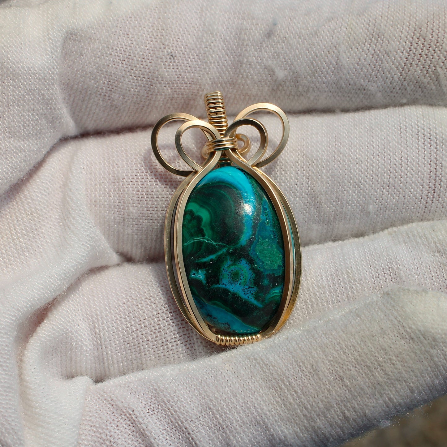 14k Gold Filled Chrysocolla Malachite pendant with intricate wire wrapping held in white gloves