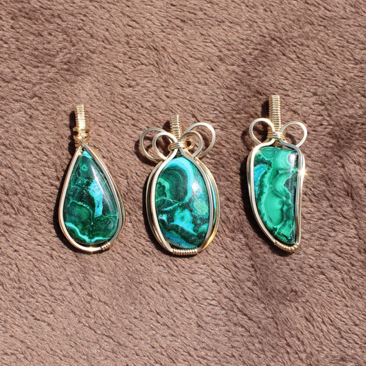Three 14k Gold Filled Chrysocolla Malachite pendants with unique green stone patterns on brown fabric