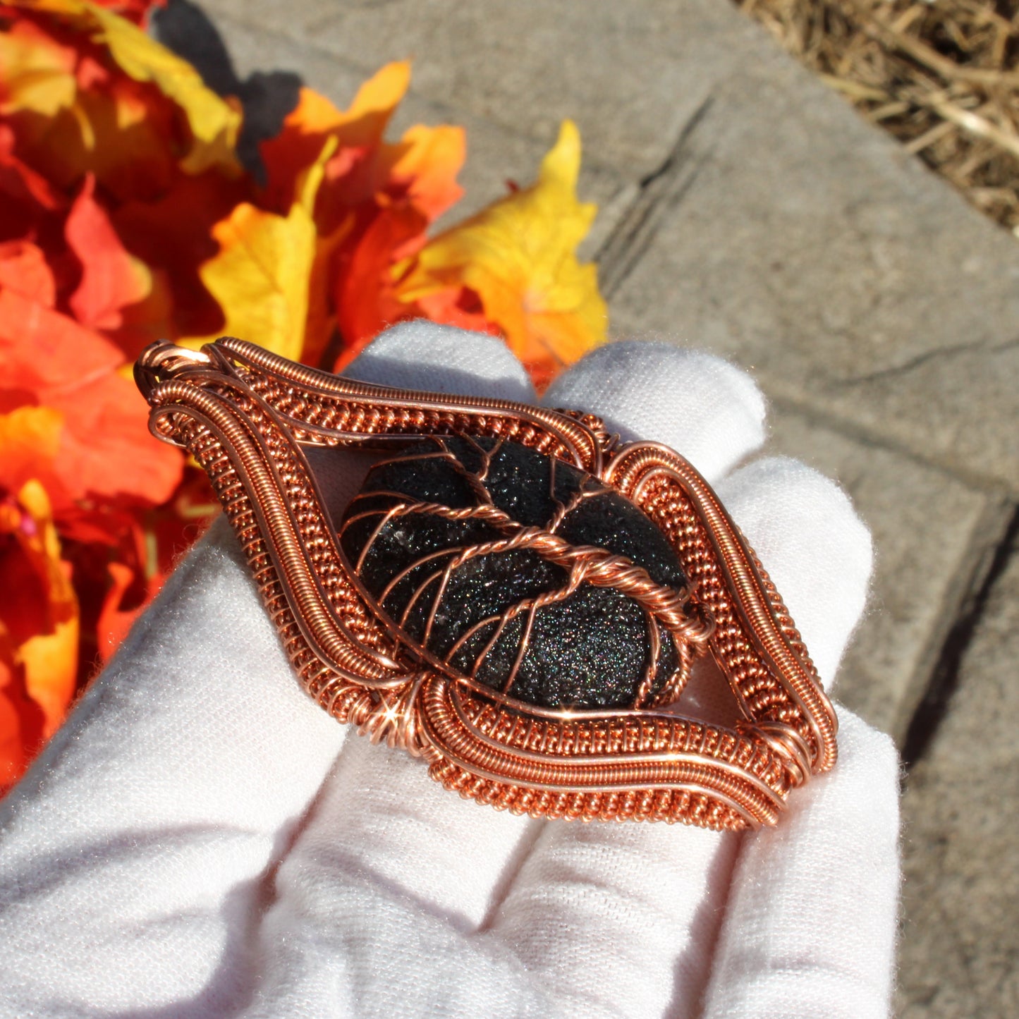 Agni Manitite Obsidian Pendant in copper wire wrapping, displayed against autumn leaves