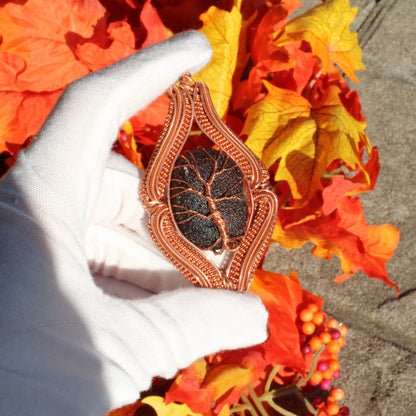 Agni Manitite Obsidian Pendant elegantly wrapped in copper showing unique texture against autumn leaves