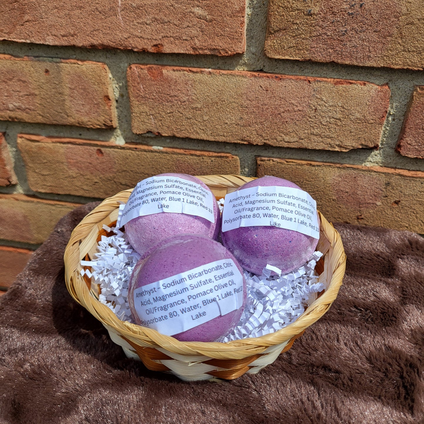 Amethyst Bath Bombs in a woven basket with decorative filling for a relaxing bath experience