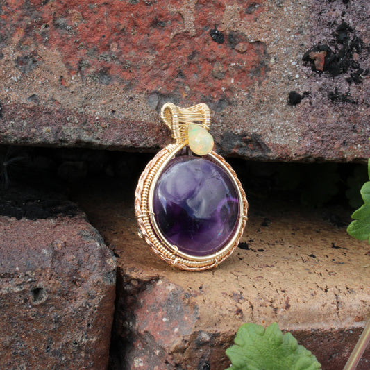 Amethyst Ethiopian Opal 14k yellow and rose gold fill pendant elegantly displayed on textured stone