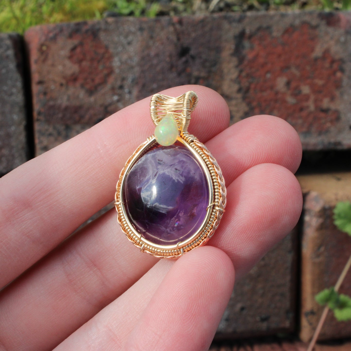 Amethyst Ethiopian Opal 14k yellow and rose gold fill pendant held in hand, showcasing its vibrant colors