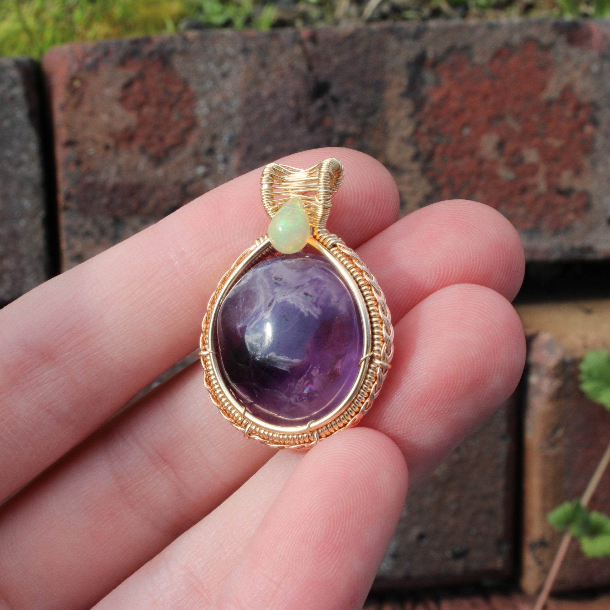 Amethyst Ethiopian Opal 14k yellow and rose gold fill pendant held in hand, showcasing its vibrant colors