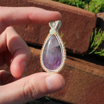 Amethyst & Ethiopian opal sterling silver pendant held in hand with natural stone textures