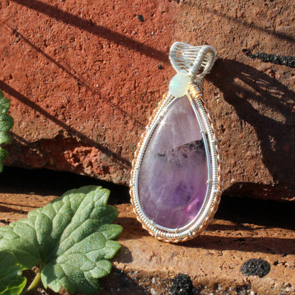 Amethyst & Ethiopian opal sterling silver pendant with unique wire wrapping design set against a natural background