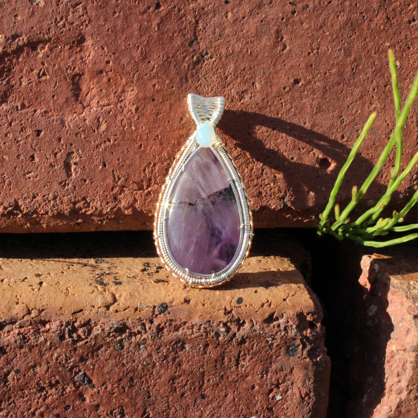Amethyst & Ethiopian opal sterling silver pendant showcased against a brick background