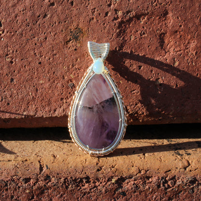 Amethyst & Ethiopian opal sterling silver pendant with intricate wire wrapping design on a rustic background