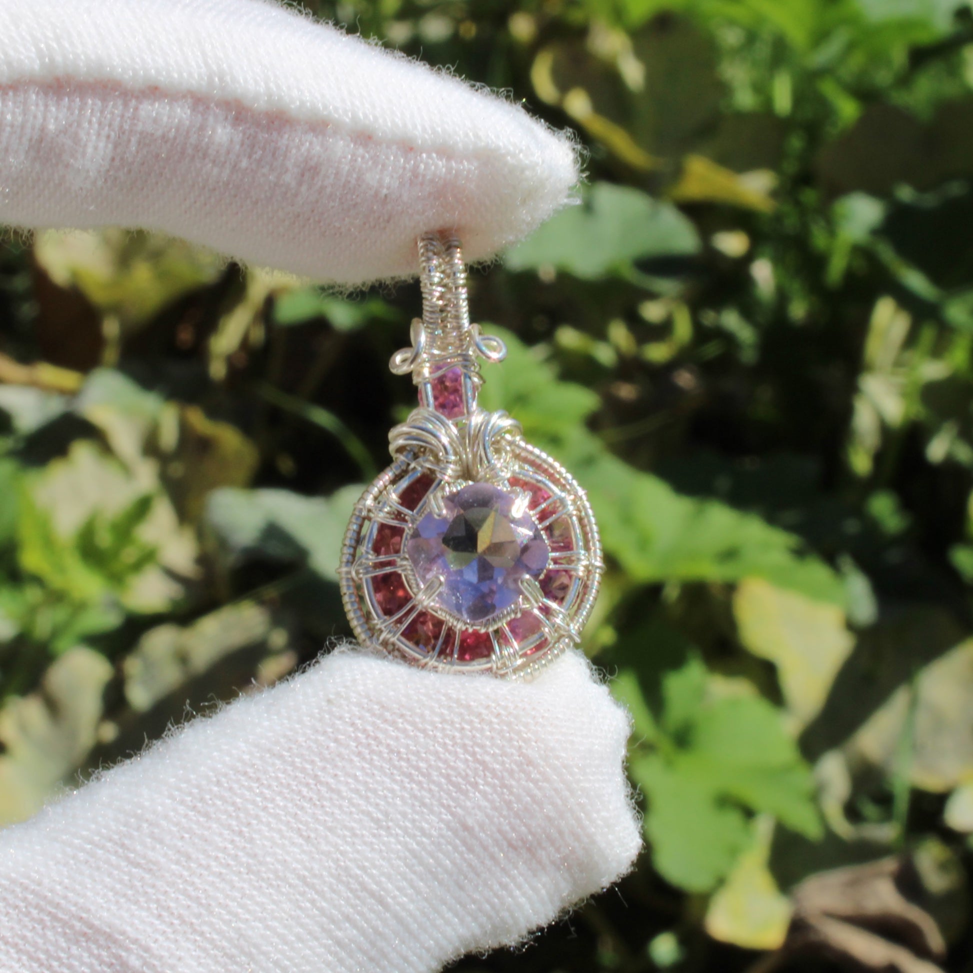 Amethyst Sterling Silver pendant with intricate design and pink tourmaline accents held by a gloved hand