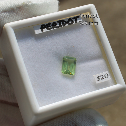 Peridot crystal 7x5 mm emerald cut in white display box labeled 20 dollars for Made to order rings