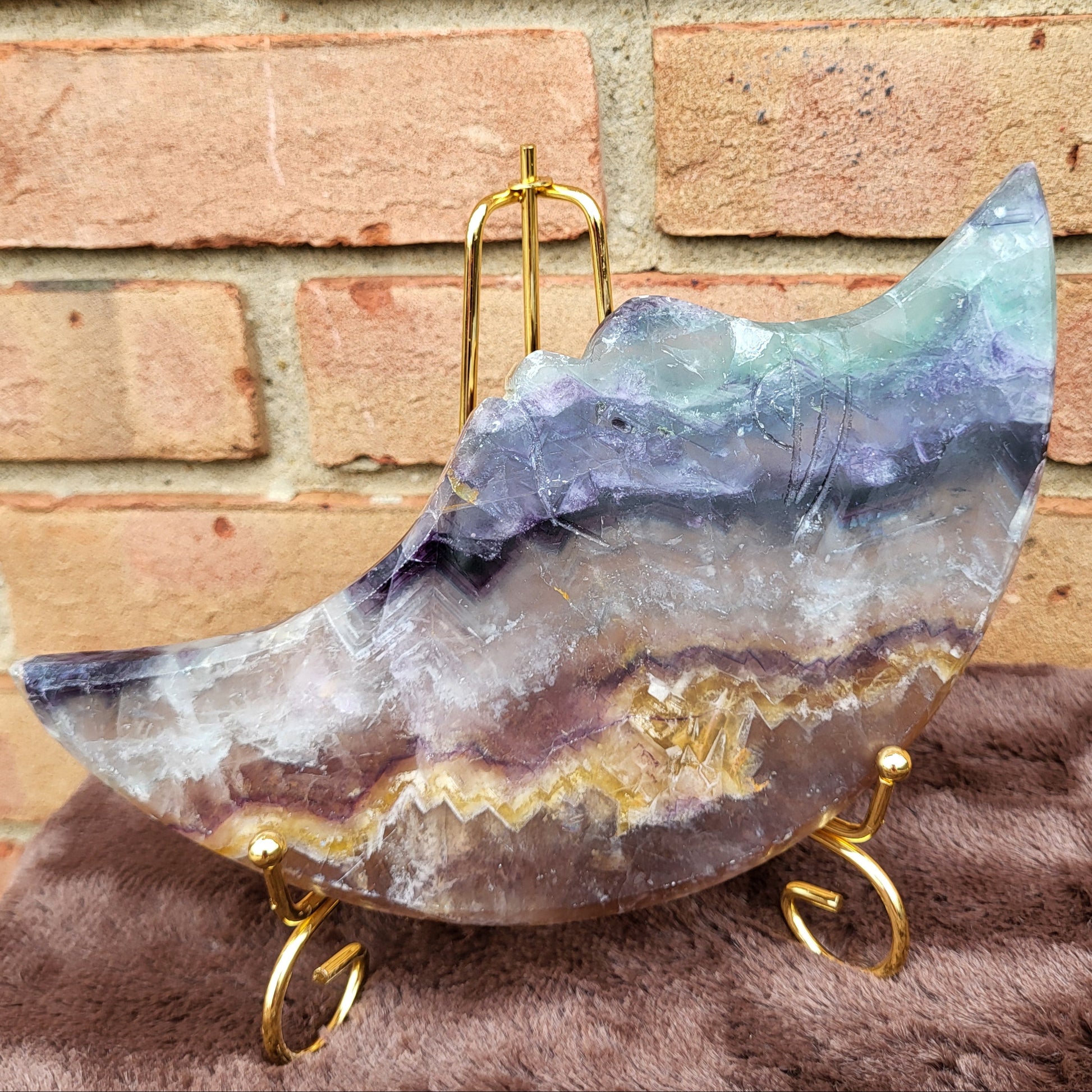 Big Rainbow Fluorite Moon displayed on a gold stand, showcasing its vibrant colors and unique patterns