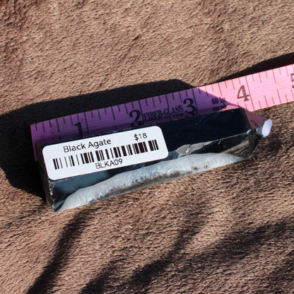 Black Agate tower collection piece displayed on a soft surface with a ruler for size reference