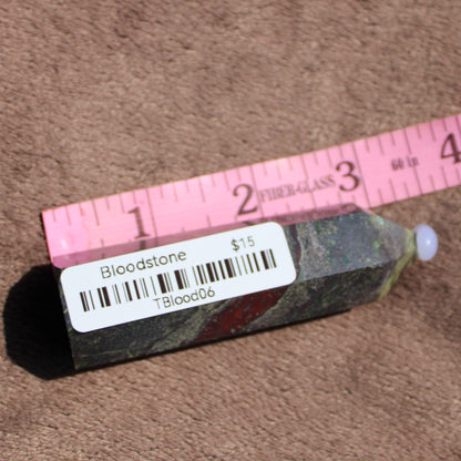 Bloodstone tower with polished surface and a clear gemstone tip, displayed with a ruler for size comparison