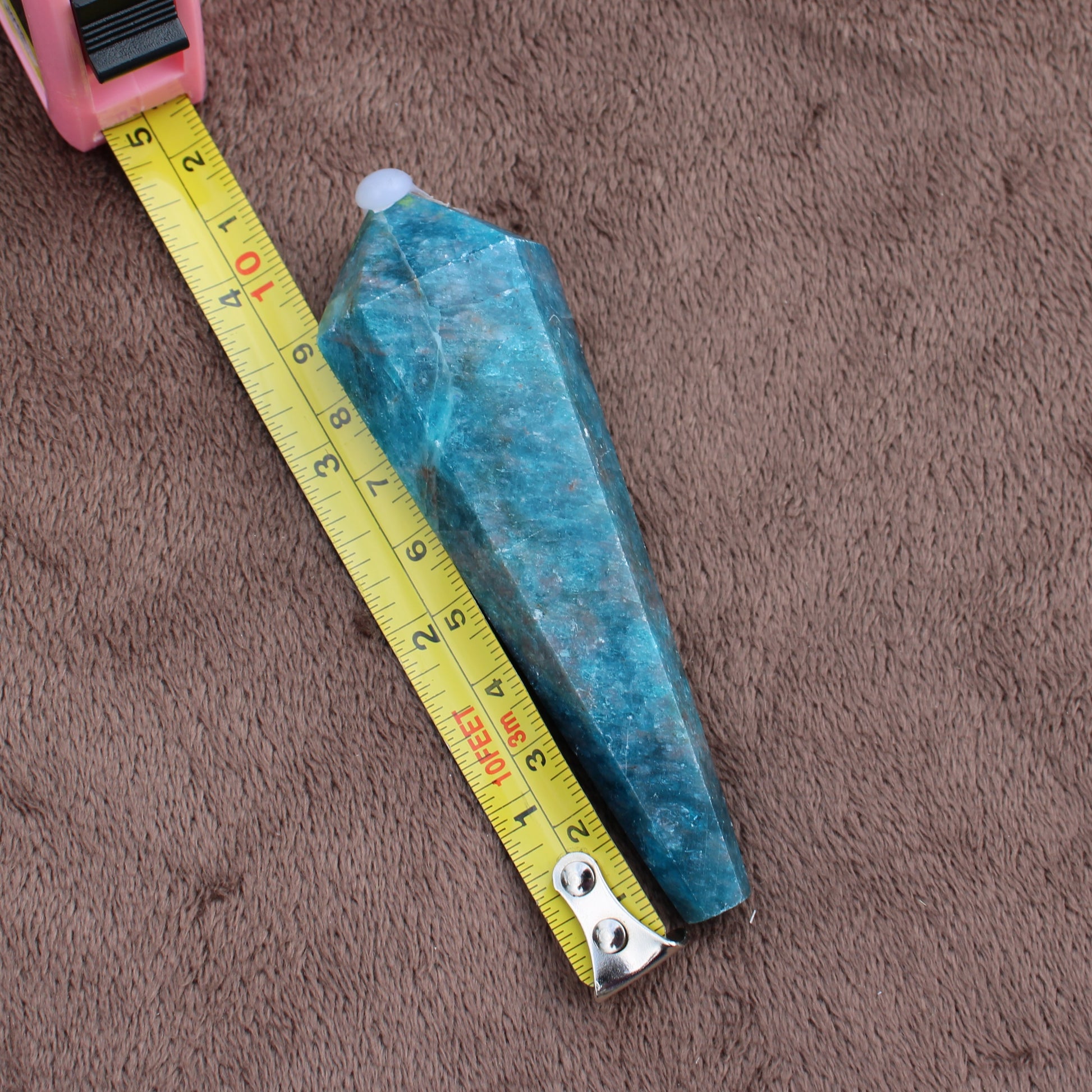 Blue Apatite Wand crystal measuring about 4 inches on a brown fabric surface