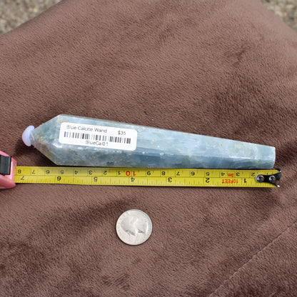 Blue Calcite Wand measuring about 6 inches placed next to a tape measure and a quarter coin